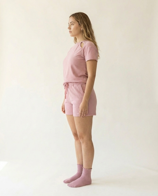 Woman wearing a pink outfit standing against a white background