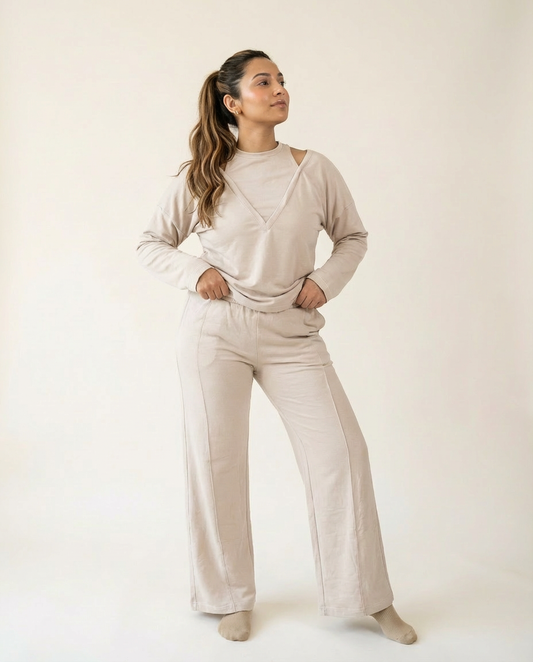 Woman wearing a beige outfit with wide-leg pants on a plain background