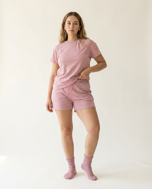 Woman wearing a pink outfit with shorts and socks on a white background