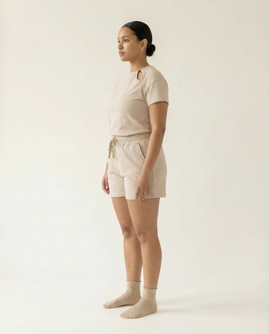 Woman wearing a beige outfit with shorts and a top on a plain background